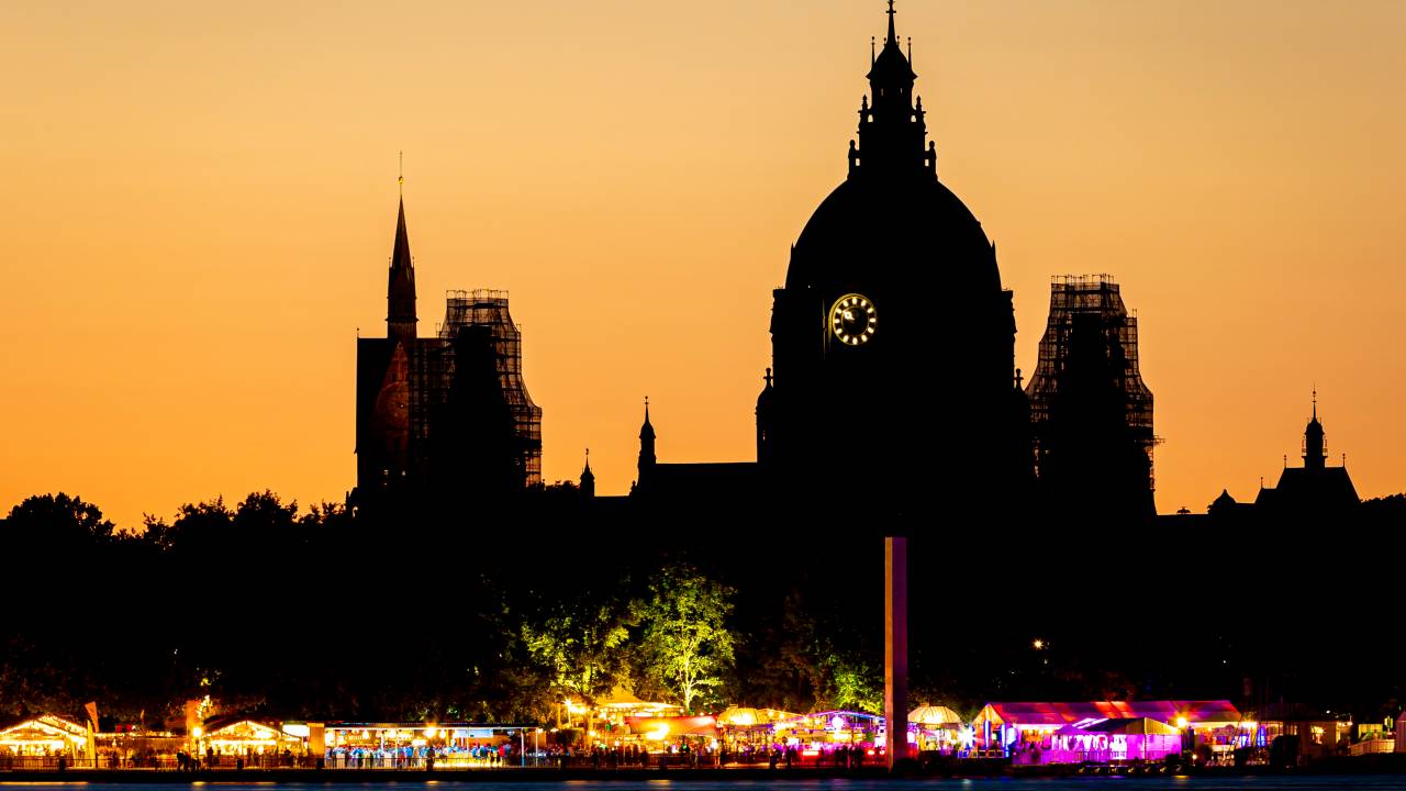 27 July 2022, Lower Saxony, Hanover: The lights of the colorfully illuminated booths of the 35th Maschseefest can be seen in the evening at the Maschsee next to the dome of the New City Hall and the tower of the Market Church. (Shot with long exposure time) Photo: Moritz Frankenberg/dpa (Photo by Moritz Frankenberg/picture alliance via Getty Images)