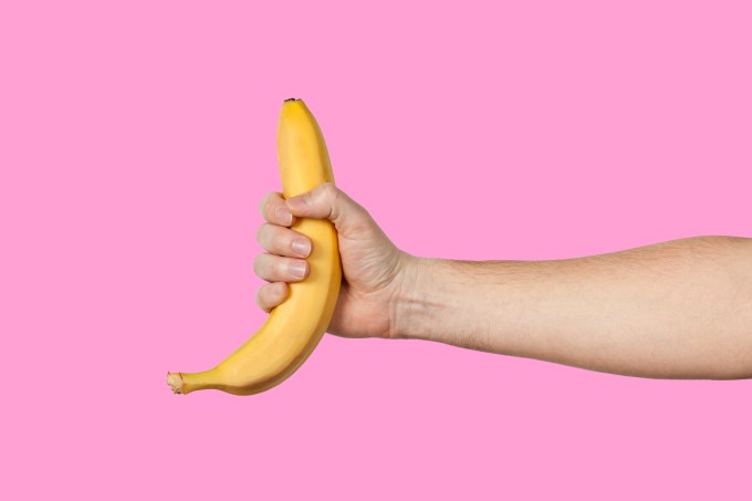 Banana as a symbol of male penis in hand on a yellow background hidden by censorship. Sexual masturbation and orgasm, impotence problem. Self-pleasure concept