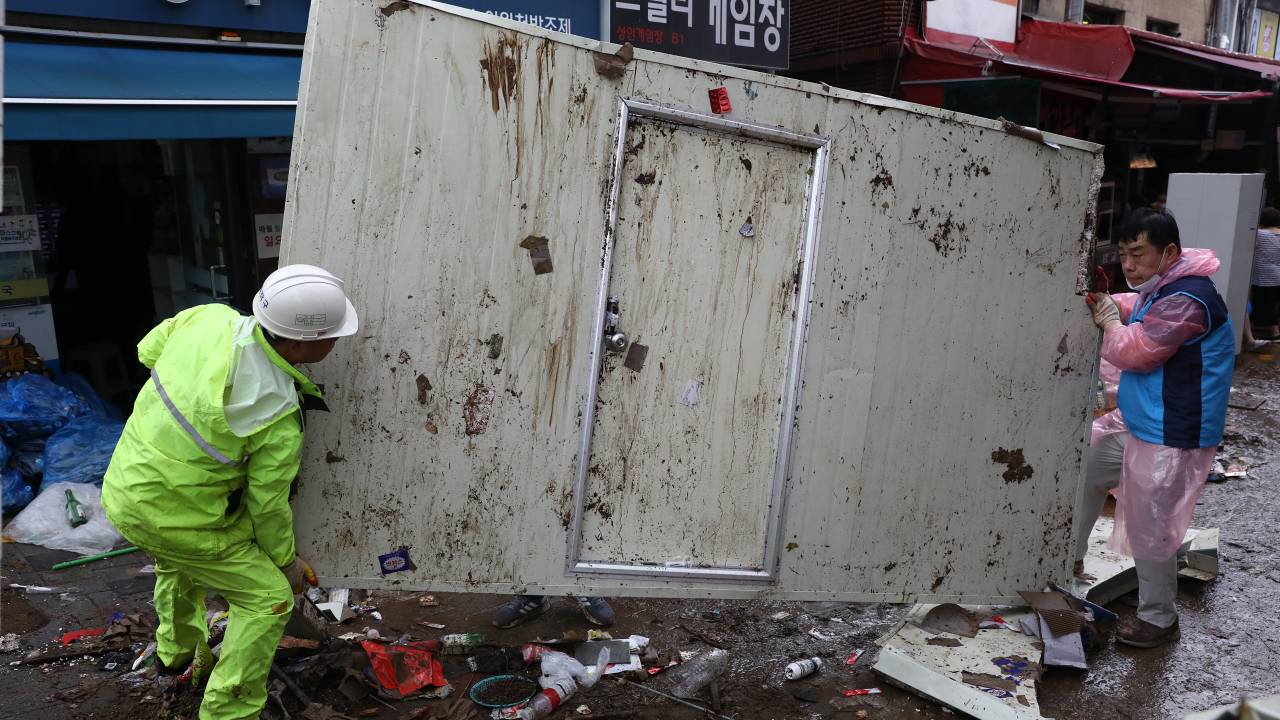 SEOUL, SOUTH KOREA - AUGUST 09: People clean up debris at a traditional market damaged by flood after torrential rain on August 09, 2022 in Seoul, South Korea. The heaviest rainfall in 80 years has pounded Seoul and surrounding regions, leaving seven people dead and six others missing, as well as flooding homes, vehicles, buildings and subway stations, government officials said. (Photo by Chung Sung-Jun/Getty Images)