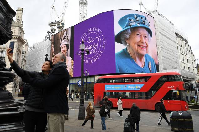 Um casal tira uma selfie enquanto as imagens da rainha Elizabeth II da Grã-Bretanha são exibidas - Um casal tira uma selfie enquanto as imagens da rainha Elizabeth II da Grã-Bretanha são exibidas -