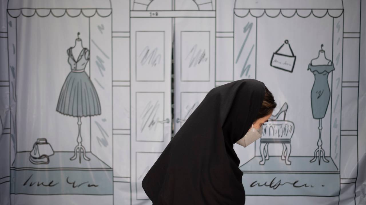 An Iranian woman walks past a shop window covered with a banner in northern Tehran on July 9, 2022. Iranian President Ebrahim Raisi called in a meeting with officials on Wednesday lack of compliance with hijab rules promotion of corruption in an Islamic country such as Iran. (Photo by Morteza Nikoubazl/NurPhoto via Getty Images)