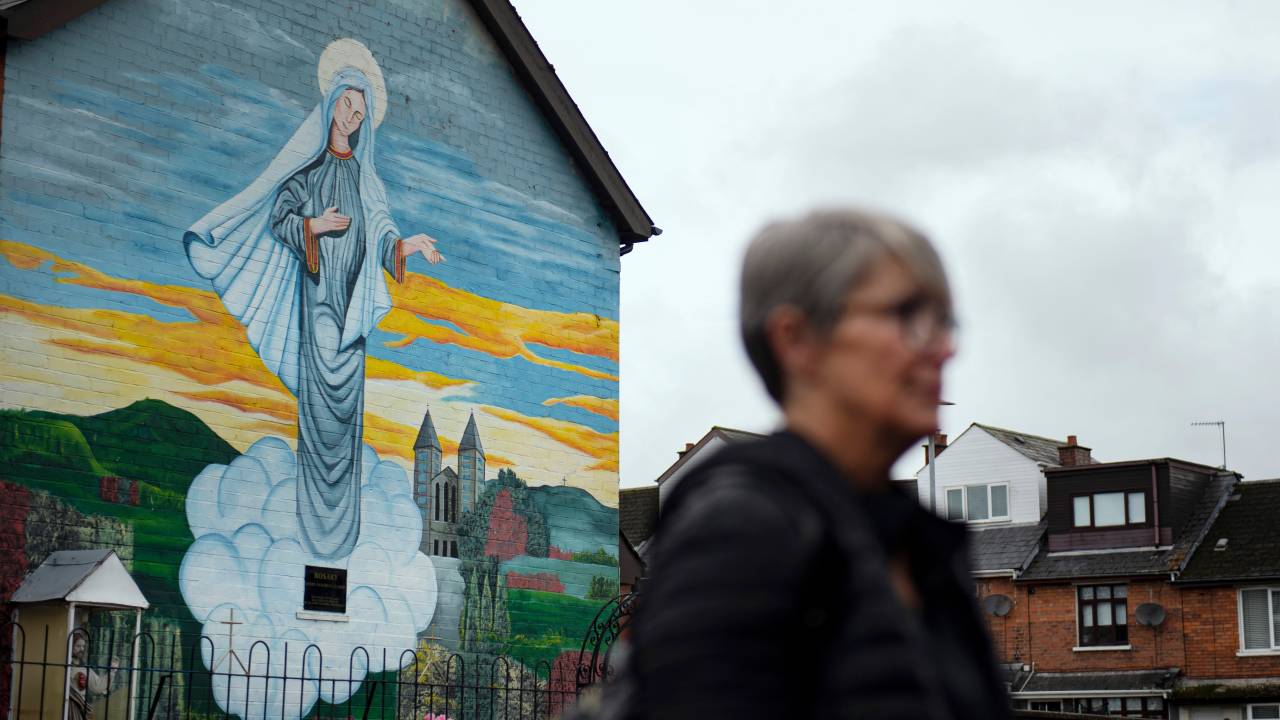 BELFAST, NORTHERN IRELAND - SEPTEMBER 22: A woman walks past a Catholic religious mural on the day that the Northern Ireland census was released on September 22, 2022 in Belfast, Northern Ireland. The latest census figures show that for the first time in Northern Irelands 101-year history there are more people from a Catholic background in Northern Ireland than Protestant. The proportion of the resident population which is either Catholic is 45.7% compared to 43.48% Protestant. The previous census, in 2011, found that 45.1% of the population were Catholic compared to 48.4% who were from a Protestant or other Christian background. (Photo by Charles McQuillan/Getty Images)