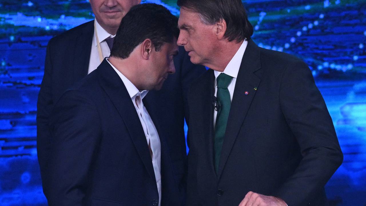 Brazilian President and presidential candidate Jair Bolsonaro (R) speaks with former Minister of Justice Sergio Moro (L) during a televised presidential debate in Sao Paulo, Brazil, on October 16, 2022. - President Jair Bolsonaro and former President Luiz Inácio Lula da Silva face each other this Sunday night in the first face-to-face debate, in which they will try to take advantage 14 days before the second round of the presidential elections in Brazil. (Photo by NELSON ALMEIDA / AFP)