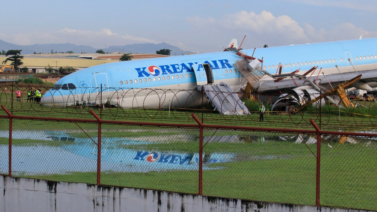 The plane of Korean Air flight KE631 lies with its belly on the runway at the airport in Cebu City, central Philippines on October 24, 2022, after it overshot the runway late October 23 while landing in bad weather. - A Korean Air plane slid off the runway in central Philippines, causing slight injuries and shutting down the country's second busiest airport, authorities said on October 24. (Photo by Alan TANGCAWAN / AFP)