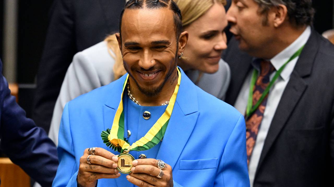 British F1 driver Lewis Hamilton shows his medal after being awarded the Honorary Brazilian Citizenship, during a ceremony at the National Congress, in Brasilia on 7 November 2022. (Photo by EVARISTO SA / AFP)a