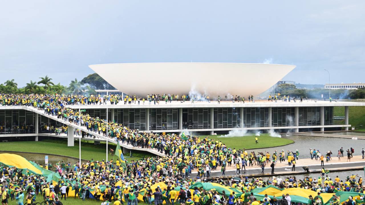 Supporters of Brazilian former President Jair Bolsonaro hold a demonstration at the Esplanada dos Ministerios in Brasilia on January 8, 2023. - Brazilian police used tear gas Sunday to repel hundreds of supporters of far-right ex-president Jair Bolsonaro after they stormed onto Congress grounds one week after President Luis Inacio Lula da Silva's inauguration, an AFP photographer witnessed. (Photo by EVARISTO SA / AFP)
