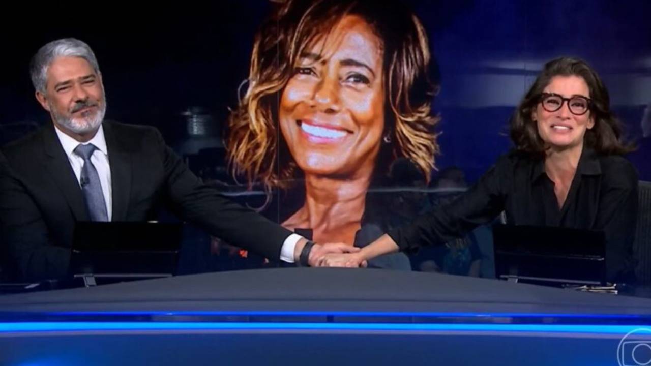 William Bonner e Renata Vasconcellos no 'Jornal Nacional', da Globo, com imagem de Glória Maria no telão ao fundo