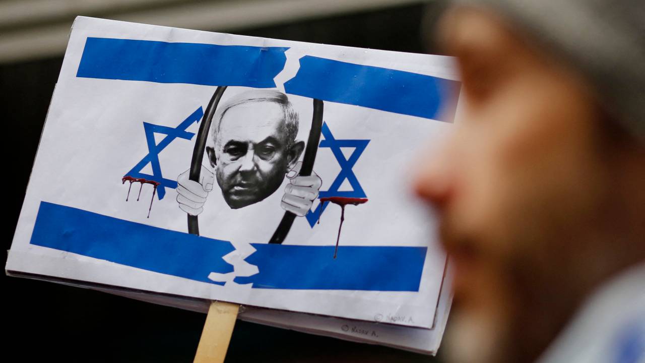 A picture of Israel's Prime Minister Benjamin Netanyahu behind bars is seen as members of the Israeli and Jewish community gather to protest outside the Israeli Consulate in New York, March 27, 2023, during an emergency rally for Israeli democracy. - Israel's Prime Minister Benjamin Netanyahu on the night of March 27, 2023, paused a judicial overhaul which triggered a general strike, political division and mass protests in the country's most severe domestic crisis in years. After nearly three months of increasing tensions, Netanyahu said in a broadcast: "Out of a sense of national responsibility, out of a will to prevent a rupture among our people, I have decided to pause the second and third readings of the bill." (Photo by Leonardo Munoz / AFP)