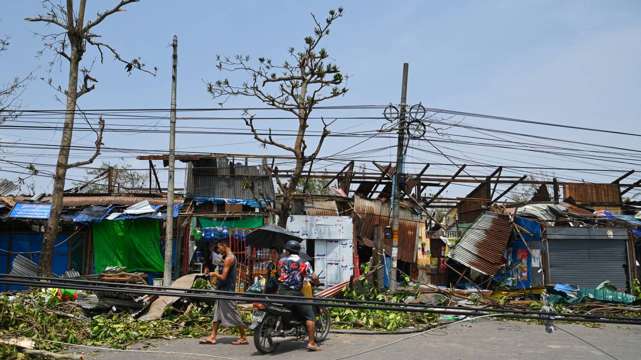 People pass damaged structures in Sittwe in Myanmar's Rakhine state on May 15, 2023, after cyclone Mocha made landfall. Cyclone Mocha made landfall on May 14 between Cox's Bazar in Bangladesh and Myanmar's Sittwe carrying winds of up to 195 kilometres (120 miles) per hour, the biggest storm to hit the Bay of Bengal in more than a decade. (Photo by Sai Aung MAIN / AFP)