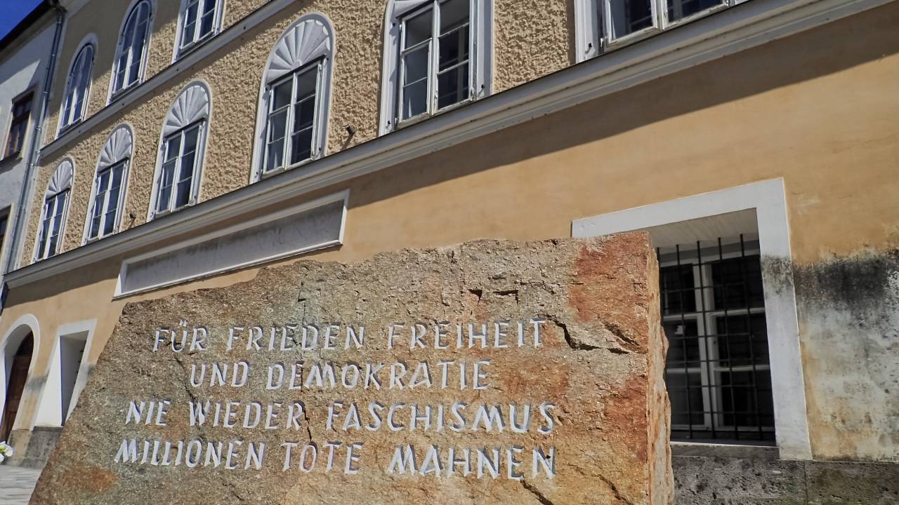 BRAUNAU AM INN, AUSTRIA - 2017/08/30: In front of Hitlers birthplace there is a stone from a stone-quarry in Mauthausen concentration camp where prisoners had to work. "For peace, freedom and democracy. Never more fascism. Millions of dead warn." is written on it.In a simple yellow house in Salzburger Vorstadt 15, Braunau am Inn, where his parents rented a small flat, Adolf Hitler was born on April 20th 1889. He later became the worst criminal in the history. In his birthplace in the Austrian town Braunau am Inn they try to forget him. They want to avoid the neo-nazi to make a pilgrimage site from this place. That´s why the state expropriated the building from the owner, Gerlinde Pommer - Angloher, last year, and plan to rebuild it and use it for charitative purposes. (Photo by Jana Cavojska/SOPA Images/LightRocket via Getty Images)