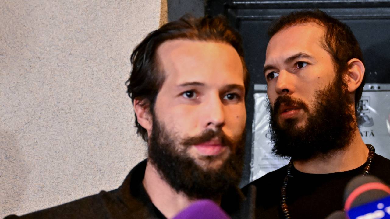 (FILES) British-US former professional kickboxer and controversial influencer Andrew Tate (R) and his brother Tristan Tate (L) walk out of the central arrest centre of Bucharest police after three months of pre-trial detention, in Bucharest, on late March 31, 2023. Online influencer Andrew Tate, his brother and two Romanian women were indicted in Romania on human trafficking and rape charges, prosecutors said on June 20, 2023, six months after they were detained. (Photo by Daniel MIHAILESCU / AFP)