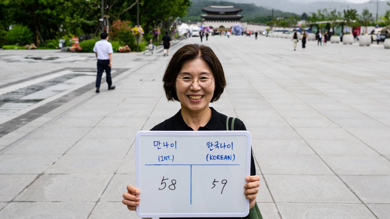 In this picture taken in Seoul on June 21, 2023, Lee Jung-hee, poses with a whiteboard showing her international age, 58, and Korean age, 59. From June 28, 2023 South Korea will use the international system that calculates age according to a person's actual date of birth, meaning everyone will officially become a year or two younger. "For people like me, who were supposed to turn 60 next year, it makes you feel like you're still young," Lee told AFP. (Photo by ANTHONY WALLACE / AFP) / To go with "SKorea-politics-culture-age", FOCUS by Cat BARTON