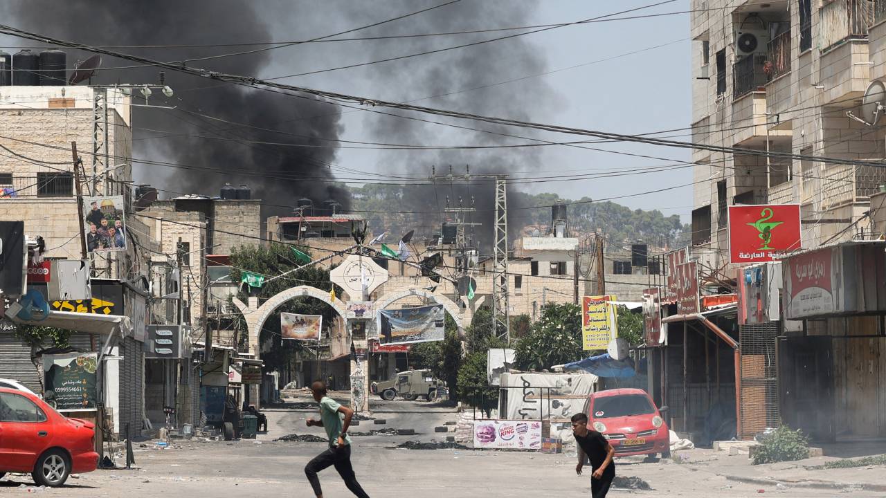 Palestinian youths run for cover amid clashes during an Israeli military operation in Jenin city in the occupied West Bank, on July 3, 2023. Israel has stepped up operations in the northern West Bank, home to Jenin city and its adjacent refugee camp, a stronghold of Palestinian armed groups where there has been a spate of attacks on Israelis as well as attacks by Jewish settlers on Palestinian communities. (Photo by Jaafar ASHTIYEH / AFP)