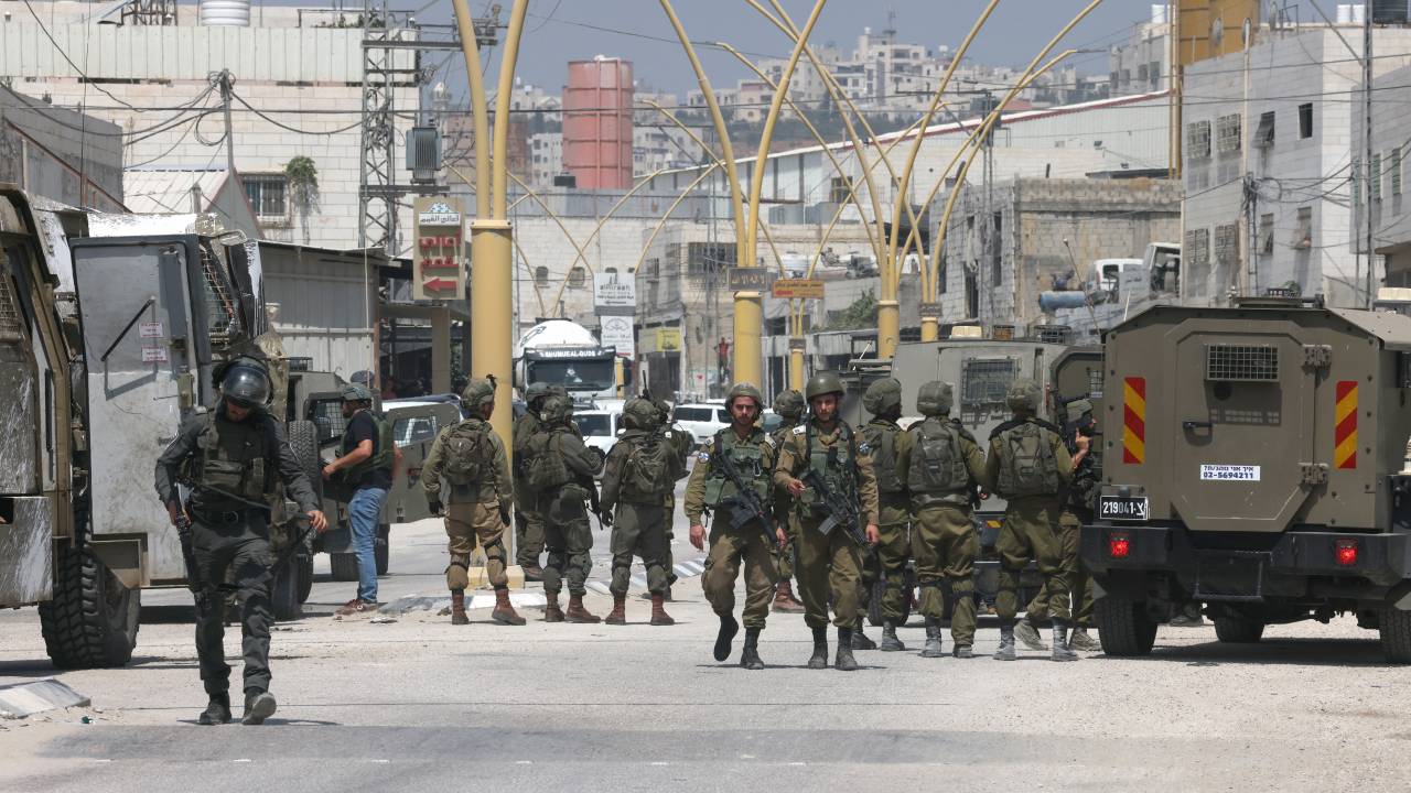 Members of Israeli security forces block a road leading to the site of a reported attack south of Hebron in the occupied West Bank, on August 21, 2023. An Israeli woman was shot dead and another man wounded in a suspected shooting attack when they were driving near Hebron on August 21, medics and the army said. (Photo by HAZEM BADER / AFP)
