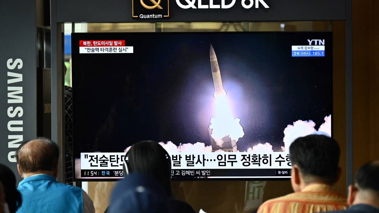 People watch a television showing a news broadcast with a photo of a North Korean missile test, at a railway station in Seoul on August 31, 2023. (Photo by Anthony WALLACE / AFP)