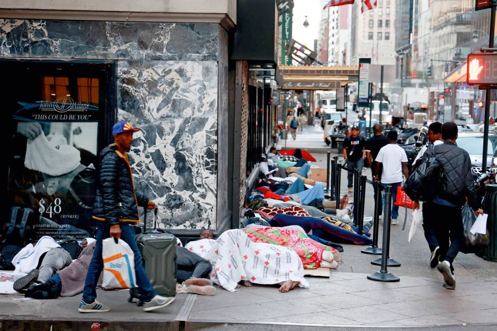 GettyImages-1569023971.jpg SEM-TETO - Imigrantes na calçada em frente a hotel lotado: medida do governo para aliviar o problema