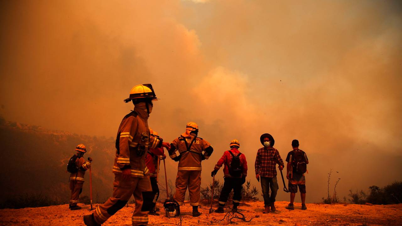 Firefighters work on the zone of a forest fire in the hills in Quilpe comune, Valparaiso region, Chile on February 3, 2024. The region of Valparaoso and Viña del Mar, in central Chile, woke up on Saturday with a partial curfew to allow the movement of evacuees and the transfer of emergency equipment in the midst of a series of unprecedented fires, authorities reported. (Photo by Javier TORRES / AFP)