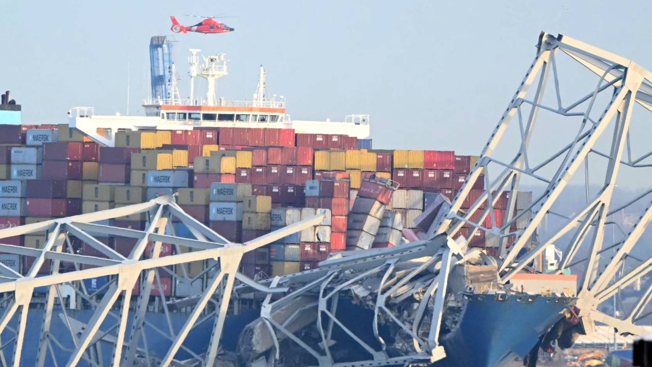 The steel frame of the Francis Scott Key Bridge sit on top of a container ship after the bridge collapsed in Baltimore, Maryland, on March 26, 2024. The bridge collapsed after being struck by a container ship, sending multiple vehicles and up to 20 people plunging into the harbor below. "Unfortunately, we understand that there were up to 20 individuals who may be in the Patapsco River right now as well as multiple vehicles," Kevin Cartwright of the Baltimore Fire Department told CNN. Ship monitoring website MarineTraffic showed a Singapore-flagged container ship called the Dali stopped under the bridge. (Photo by Mandel NGAN / AFP)
