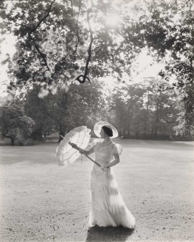 1039846-1629305044 A Rainha Mãe, esposa de George V e mãe de Elizabeth II, é fotografada no Palácio de Buckingham em 1939. Ela usa um dos vestidos que Norman Hartnell desenhou para a Visita de Estado à França em 1938, conhecido como “Guarda-roupa Branco”, que se tornou uma sensação da moda. -