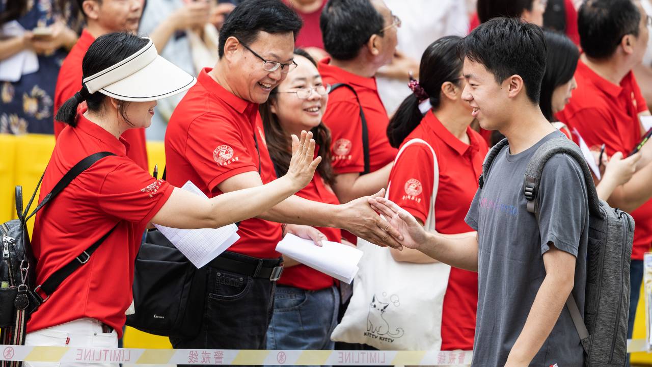 WUHAN, HUBEI, CHINA - 2024/06/07: A Chinese student high five with his teacher as he enters school to take the National College Entrance Examination, also known as Gaokao, at the No.2 High School, one of the city's most prestigious schools. Students spend months preparing for the annual examination and the results determine students educational path and future job prospects. A total of 13.42 million students are expected to take the tests over three days. (Photo by Ren Yong/SOPA Images/LightRocket via Getty Images)