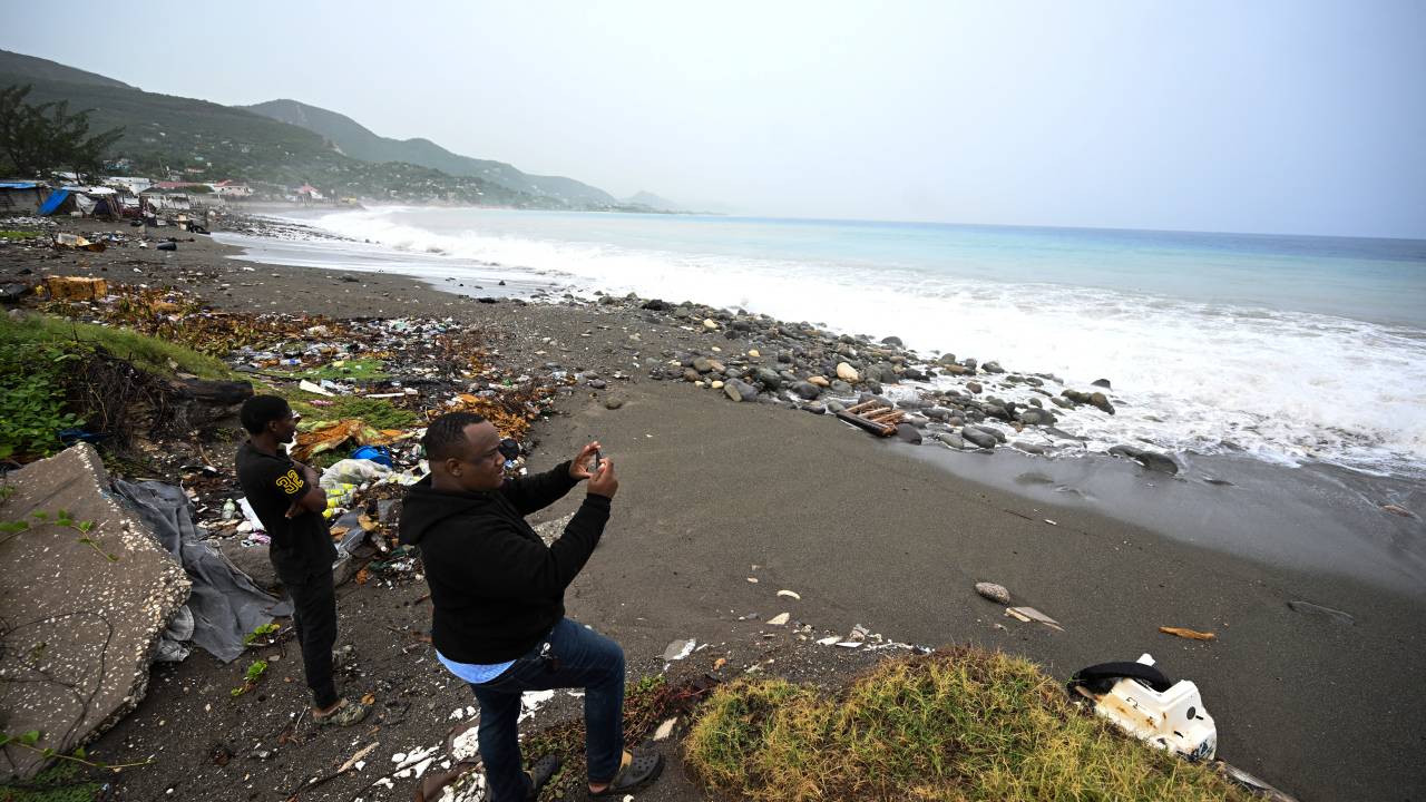 People watch as waves crash along the beach in Kingston, Jamaica, before the arrival of Hurricane Beryl on July 3, 2024. Beryl churned towards Jamaica on July 3, with forecasters warning of potentially deadly winds and storm surge, after at least seven people were killed and widespread destruction was reported across the southeastern Caribbean. The powerful hurricane, which is rare so early in the Atlantic season, was expected to pass over Jamaica around midday as a "life-threatening" Category 4 storm, meteorologists said. (Photo by Ricardo Makyn / AFP)