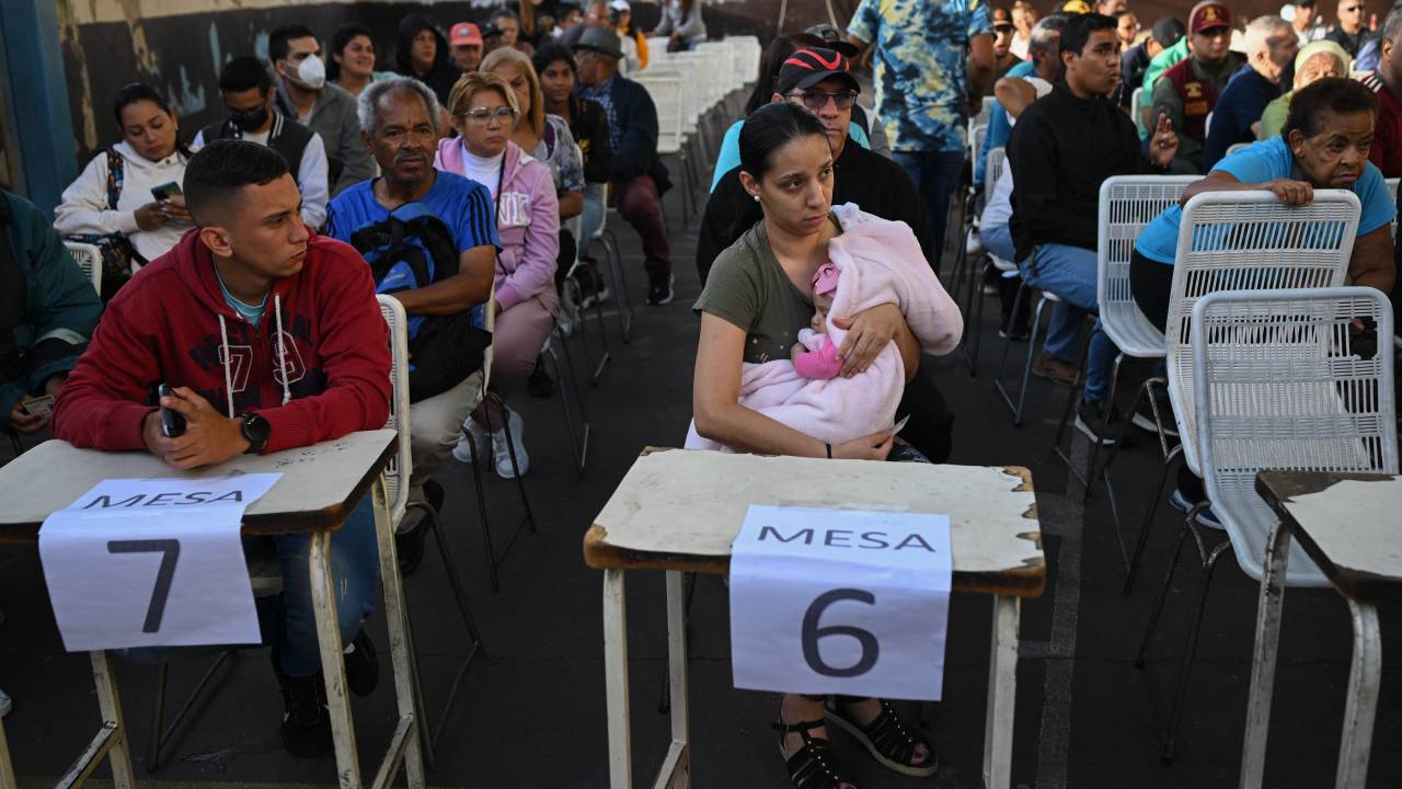 People wait for their turn to vote at a polling station in Caracas, during the Venezuelan presidential election on July 28, 2024. Venezuelans vote Sunday between continuity in President Nicolas Maduro or change in rival Edmundo Gonzalez Urrutia amid high tension following the incumbent's threat of a "bloodbath" if he loses, which polls suggest is likely. (Photo by Federico PARRA / AFP)
