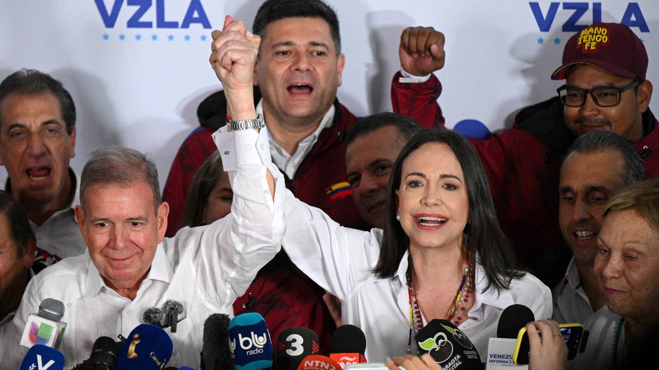 Venezuelan opposition leader Maria Corina Machado (R) speaks with the media next to opposition presidential candidate Edmundo Gonzalez Urrutia while waiting for the results of the presidential election, in Caracas on July 28, 2024. Venezuela's opposition leader Maria Corina Machado urged voters in the country's presidential election to remain at their polling stations to verify the counting process in the "decisive hours" after closing. (Photo by Federico PARRA / AFP)