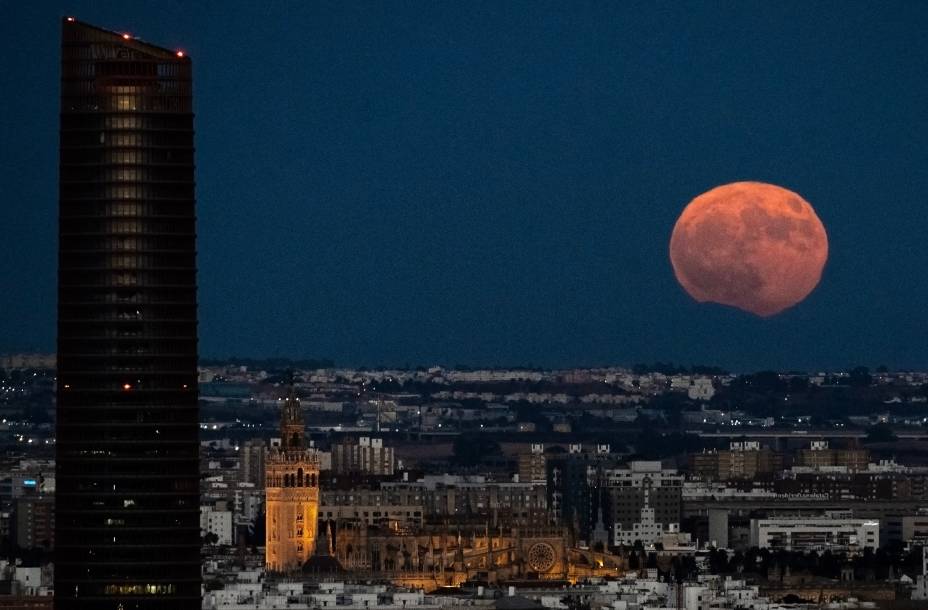 A imagem mostra a Torre Pelli e a catedral enquanto a Lua cheia nasce sobre Sevilha, na Espanha