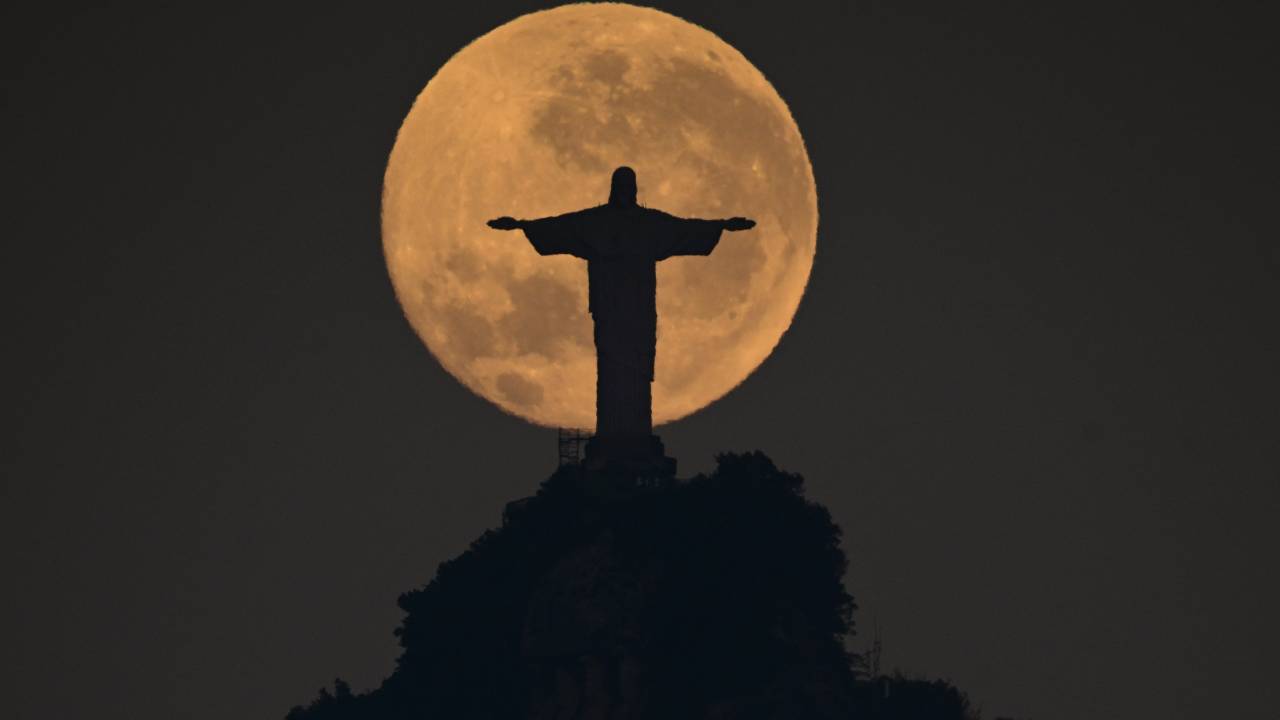 The waxing gibbous moon sets behind the Christ the Redeemer statue in Rio de Janeiro on August 20, 2024. (Photo by Pablo PORCIUNCULA / AFP)