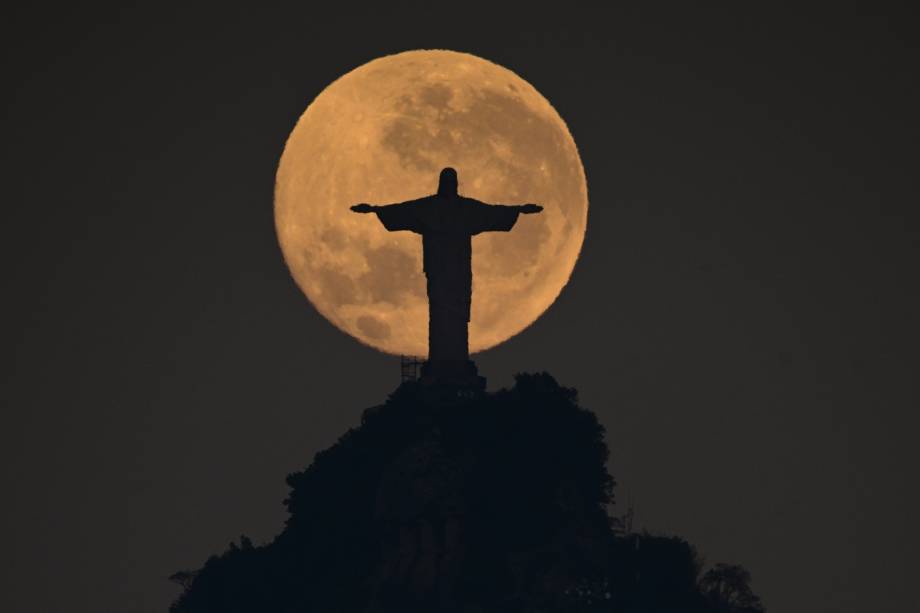 A lua se põe atrás da estátua do Cristo Redentor, no Rio de Janeiro, Brasil