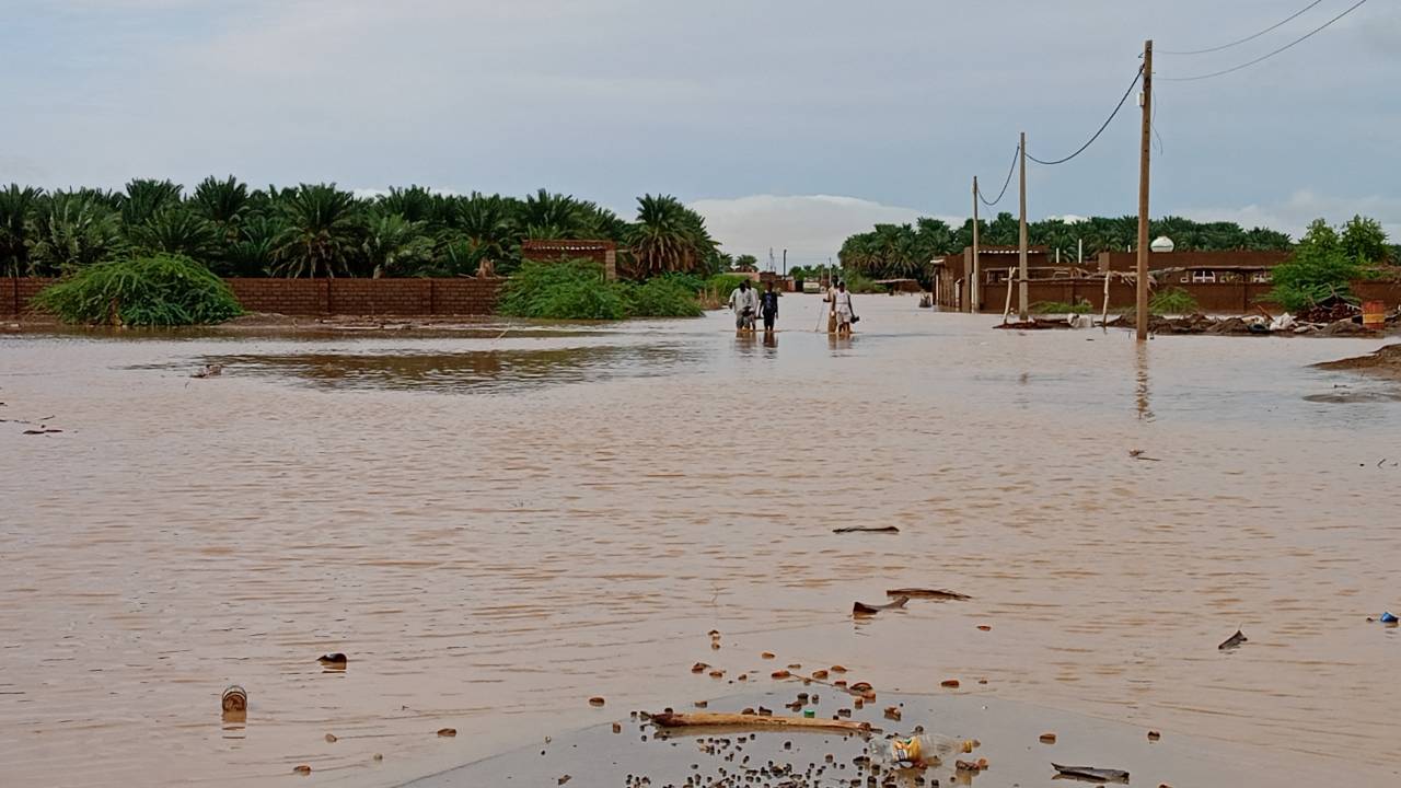 Sudaneses caminham em uma rua inundada na cidade de Tangasi, na província de Meroe, no Sudão