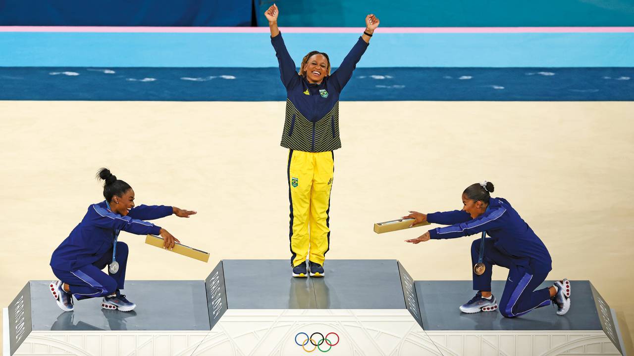 Enquanto ela celebrava sua conquista, embalada por gritos de “rainha, rainha”, Biles (à esq.) e sua colega de equipe americana Jordan Chiles, que ganhou o bronze, faziam uma merecida reverência à campeã daquela tarde