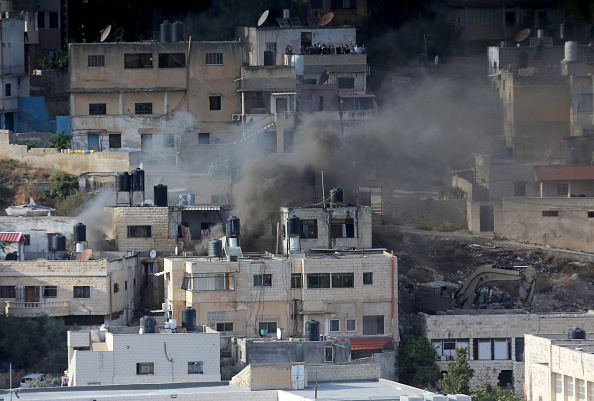 Fumaça sobe entre prédios na cidade de Qabatya, na Cisjordânia ocupada, após ataque israelense. 19/09/2024