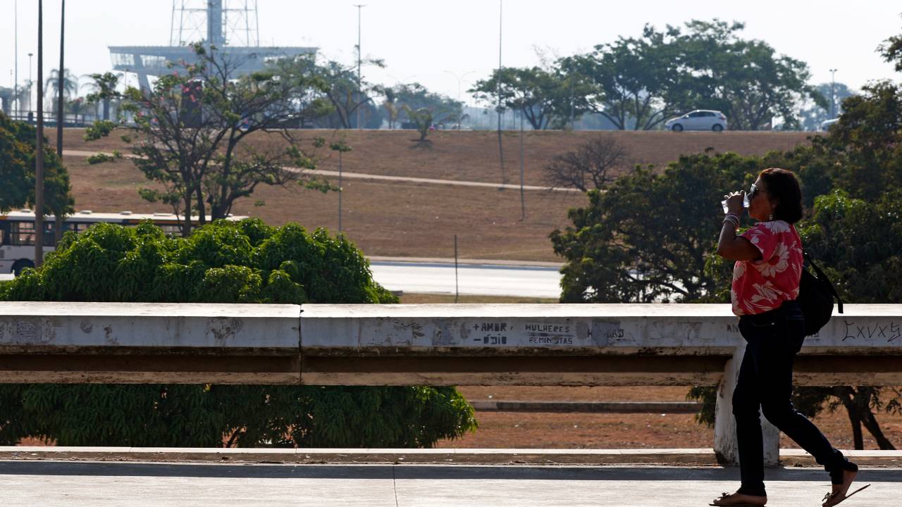 Brasília (DF), 03.09.2024 - Seca e alta temperatura em Brasília. Pessoa com copo de água passa pelo Setor de Diversões Sul. Foto: Bruno Peres/Agência Brasil