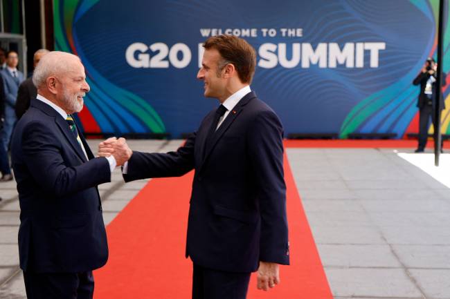 Brazil's President Luiz Inacio Lula da Silva (L) shakes hands with France's President Emmanuel Macron upon his arrival for the first day of the G20 Summit in Rio de Janeiro, Brazil, on November 18, 2024. (Photo by Ludovic MARIN / AFP)