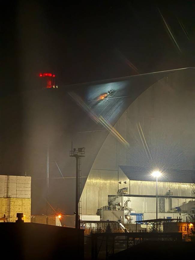 UKRAINE-RUSSIA-WAR-CHERNOBYL A handout images taken from the X account of the International Atomic Energy Agency (IAEA) on February 14, 2025 shows a glow after an UAV apparently had struck the roof at the New Safe Confinement (NSC), which protects the remains of reactor 4 of the former Chornobyl NPP, causing a fire. Ukrainian's president said on February 14, that a Russian drone had struck overnight a cover built to contain radiation at the Chernobyl nuclear power plant, adding that