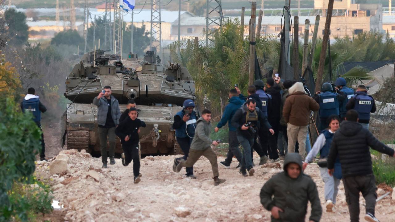 Palestinian children and journalists disperse as Israeli tanks enter the Jenin camp for Palestinian refugees in the occupied West Bank, on February 23, 2025. Israel on February 23 said troops would stay in West Bank refugee camps for the coming year, announcing expanded military operations including tank deployments, after the displacement of tens of thousands of Palestinians. (Photo by Jaafar ASHTIYEH / AFP)