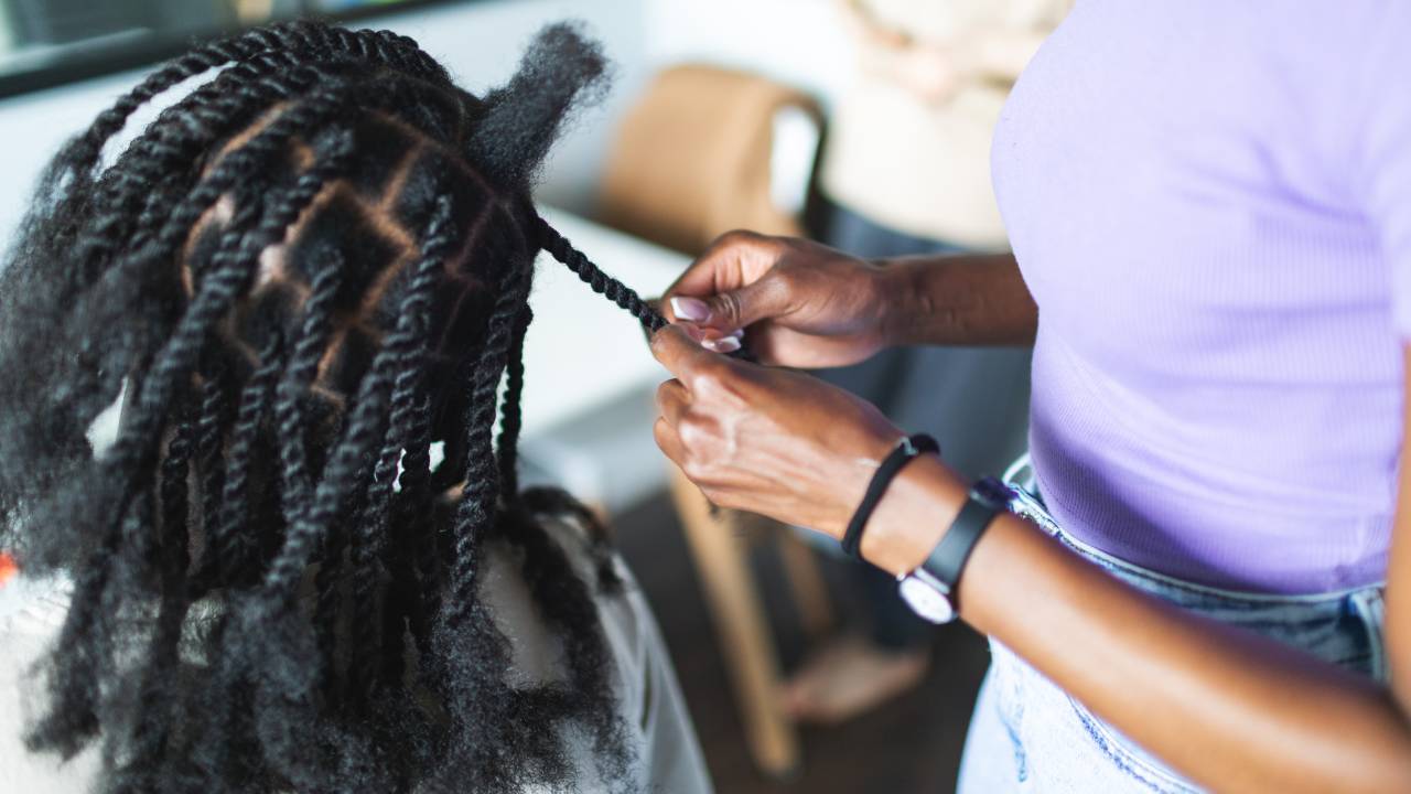 oung black woman working at home and making afro braids to young black men