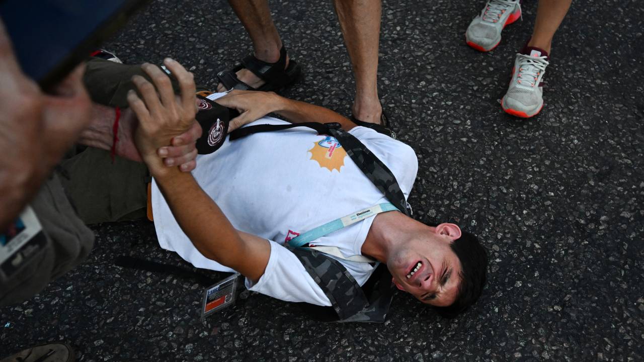 A journalist affected by tear gas gestures during a protest called by pensioners against the government of President Javier Milei, demanding an increase in pensions outside the National Congress in Buenos Aires on March 5, 2025. (Photo by Luis ROBAYO / AFP)
