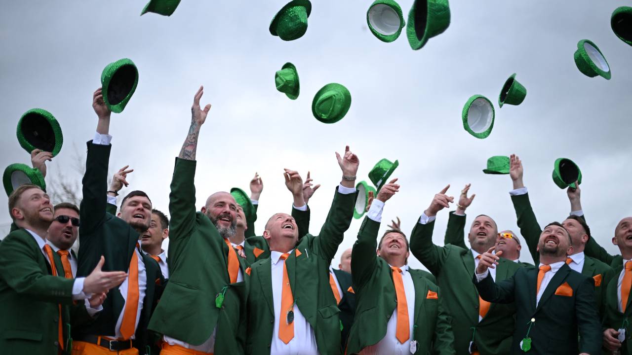 Racegoers dressed in Irish colours hurl their hats into the air as St Patrick's Day is celebrated at the course on the third day of the Cheltenham Festival at Cheltenham Racecourse, in Cheltenham, western England on March 13, 2025. (Photo by JUSTIN TALLIS / AFP)