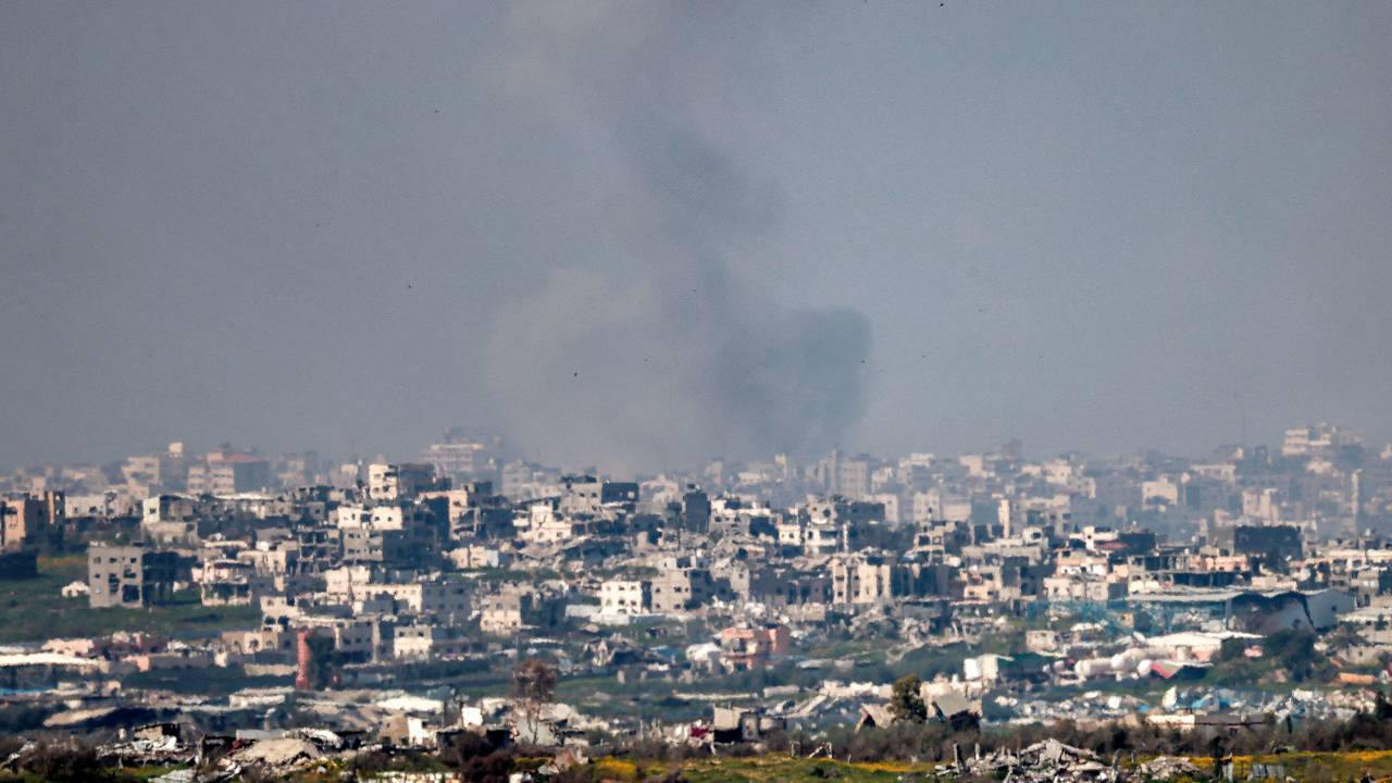 A cloud of smoke billows as destroyed buildings are pictured in the northern Gaza Strip from across the border in southern Israel on March 18, 2025. Israel on March 18 unleashed its most intense strikes on the Gaza Strip since a January ceasefire, with rescuers reporting 220 people killed, and Hamas accusing Benjamin Netanyahu of deciding to "resume war" after a deadlock on extending the truce. (Photo by Menahem KAHANA / AFP)
