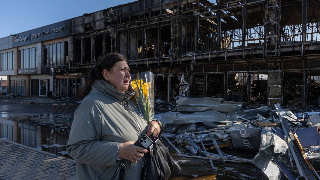Mulher segurando flores se depara com prédios destruídos na cidade de Odessa, no sul da Ucrânia, após ataque com drones russos. 21/03/2025