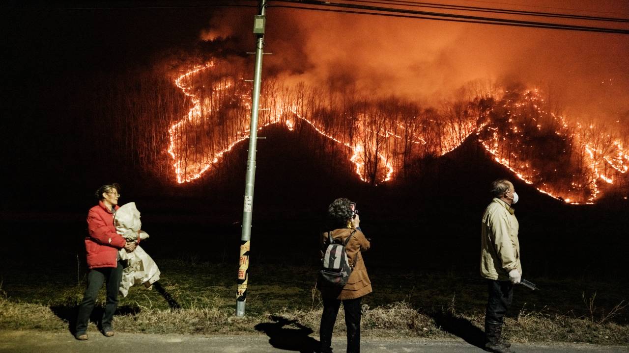 Moradores assistem a incêndios florestais sob um poste de luz em Uiseong, Coreia do Sul, em 24 de março de 2025