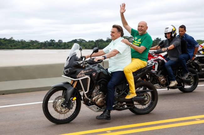O então presidente Jair Bolsonaro e o empresário Luciano Hang, ambos sem capacete, andam de moto em ponte sobre o rio Madeira, na BR-364, em Rondônia, no dia 7 de maio de 2021