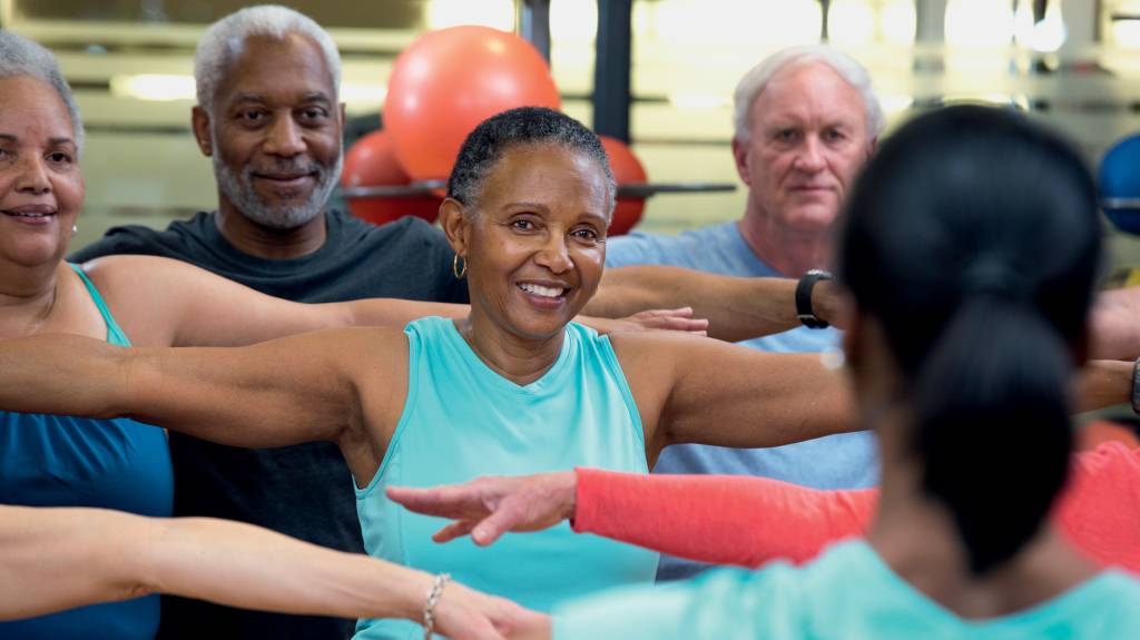 People practicing yoga together in class EM COMUNIDADE - Longe da solidão: vida social ativa está associada a menor índice de mortalidade precoce