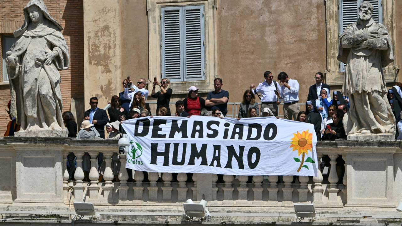 Members of the public old a banner reading "Too human" as they attend the funeral ceremony of late Pope Francis at St Peter's Square at the Vatican on April 26, 2025. (Photo by Alberto PIZZOLI / AFP)