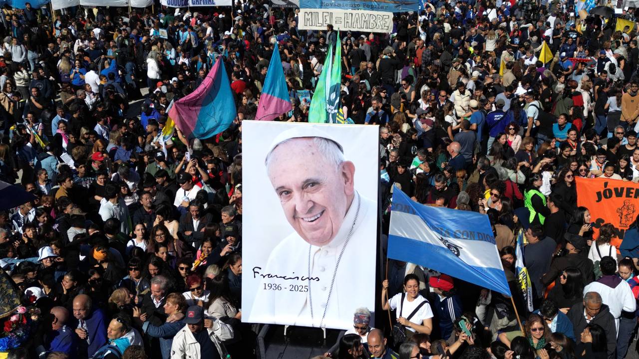 A military vehicle carries an image of Pope Francis during a pilgrimage through Buenos Aires on April 26, 2025, after a mass to bid him farewell. With songs, candles, flags, and prayers, Buenos Aires mourners marked the burial of pontiff and native son Pope Francis on Saturday. As the 88-year-old was being laid to rest an ocean away in Rome, thousands gathered by Buenos Aires' cathedral for dawn vigils and a mass of remembrance. (Photo by Luis ROBAYO / AFP)