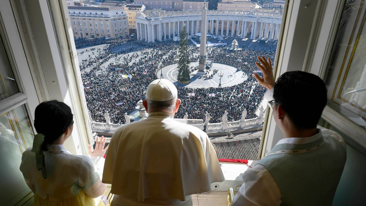 VATICAN CITY, VATICAN - NOVEMBER 24: (EDITOR NOTE: STRICTLY EDITORIAL USE ONLY - NO MERCHANDISING) Pope Francis, flanked by two Korean youths, waves to the faithful gathered in St. Peter's Square during his Sunday Angelus blessing on the World Youth Day on November 24, 2024 in Vatican City, Vatican. Pope Francis greeted delegations of young people from Portugal and South Korea in Rome for Sunday's 39th World Youth Day on the Solemnity of Christ the King as the WYD symbols, the Cross and the icon of Mary Salus Populi Romani, are passed from the Portuguese to the Koreans who will host the next world youth gathering in Seoul in 2027. (Photo by Vatican Media via Vatican Pool/Getty Images)