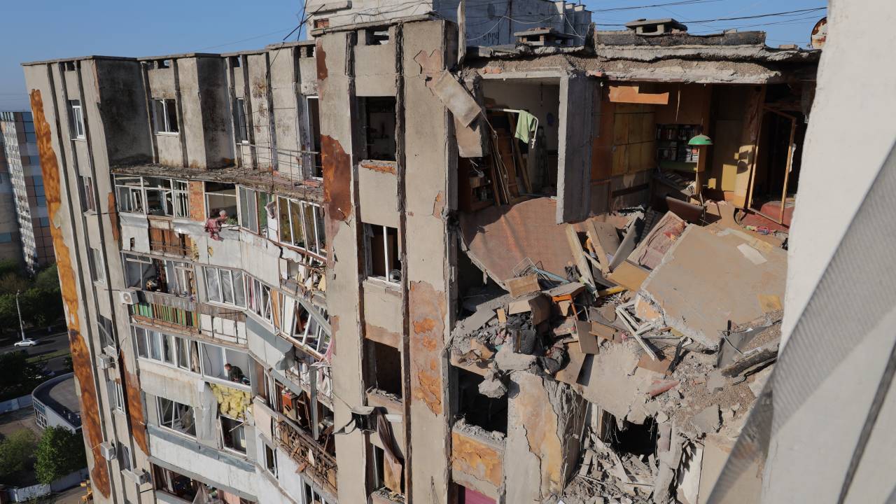 Local residents look out of broken windows in a damaged residential building following a drone attack in Odesa on May 1, 2025, amid the Russian invasion of Ukraine. A Russian drone strike overnight killed at least two people and wounded 15 others in a residential area of Odesa, the Ukrainian emergency services said early on May 1, 2025. (Photo by Oleksandr GIMANOV / AFP)