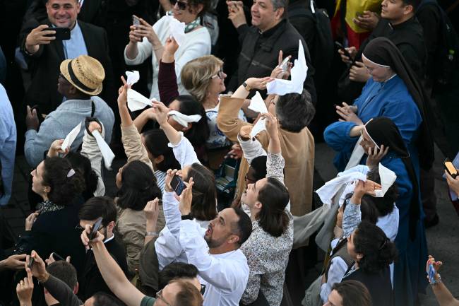 People react as white smoke (unseen) signals that cardinals elected a new pope during their conclave in the Vatican on May 8, 2025. (Photo by Gabriel BOUYS / AFP)